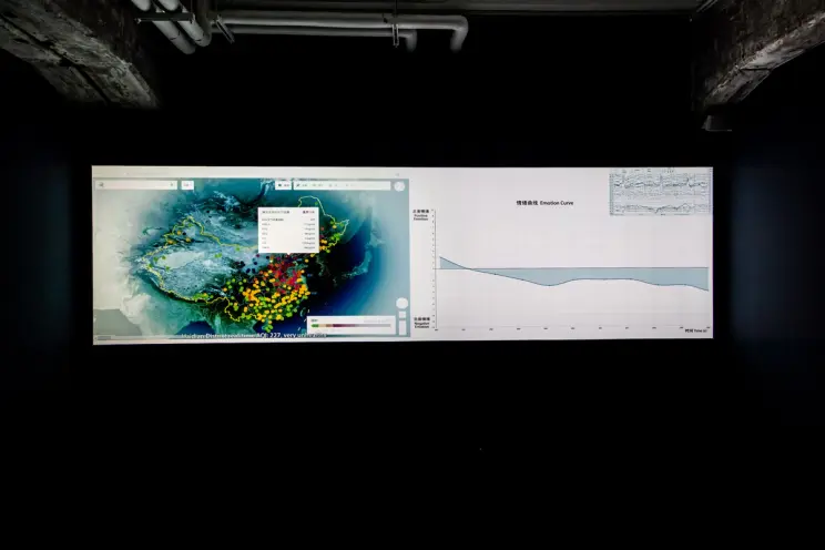 Two large screens showing a map and graph against a dark background.