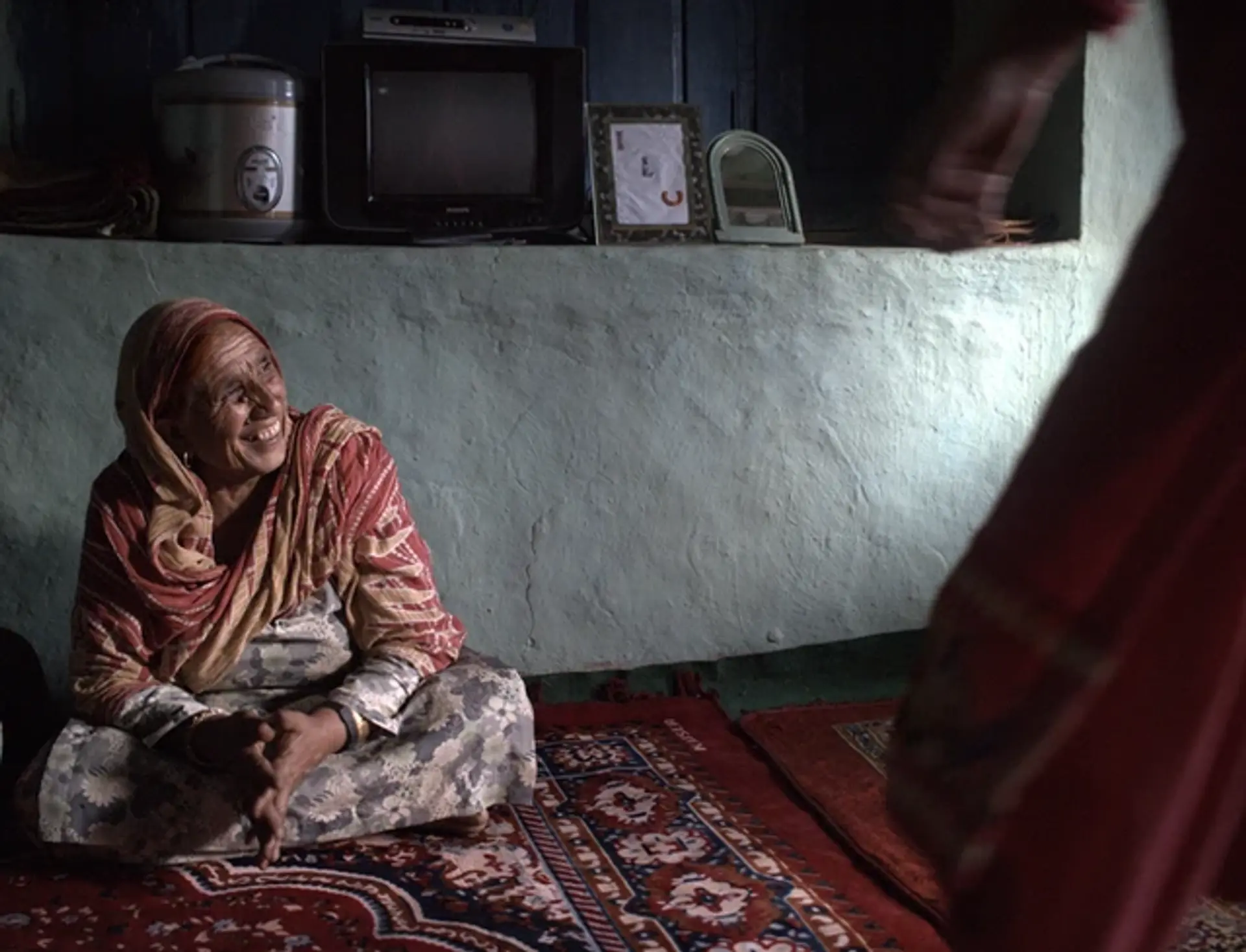 Elderly woman laughing in a home setting with rustic decor.