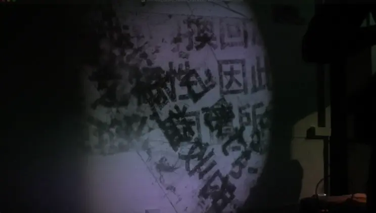 Projected text in black Chinese characters appears distorted in a dimly lit space.