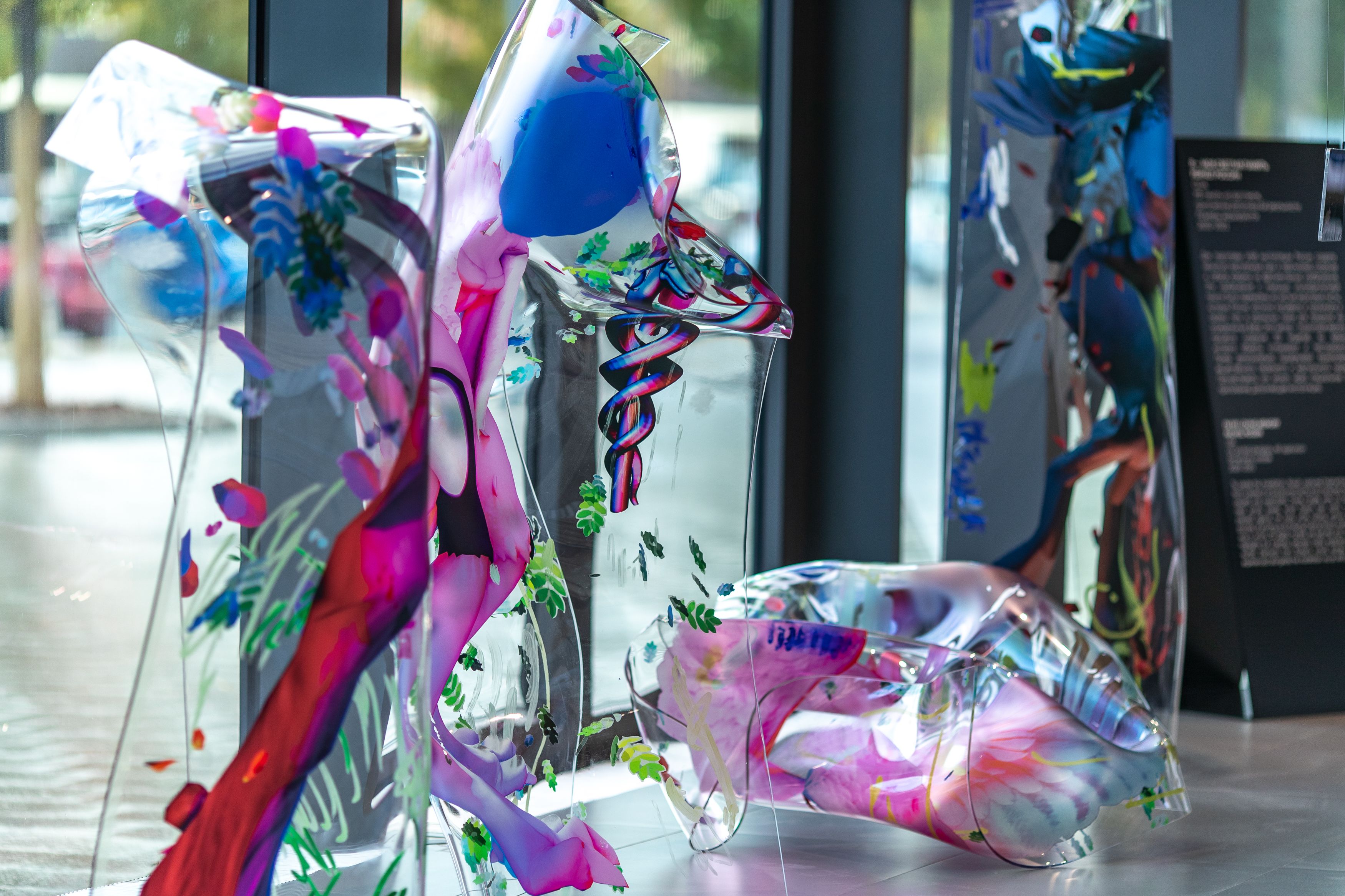 Transparent, water-colored plastic forms situated near a window, with a black informative flyer nearby.
