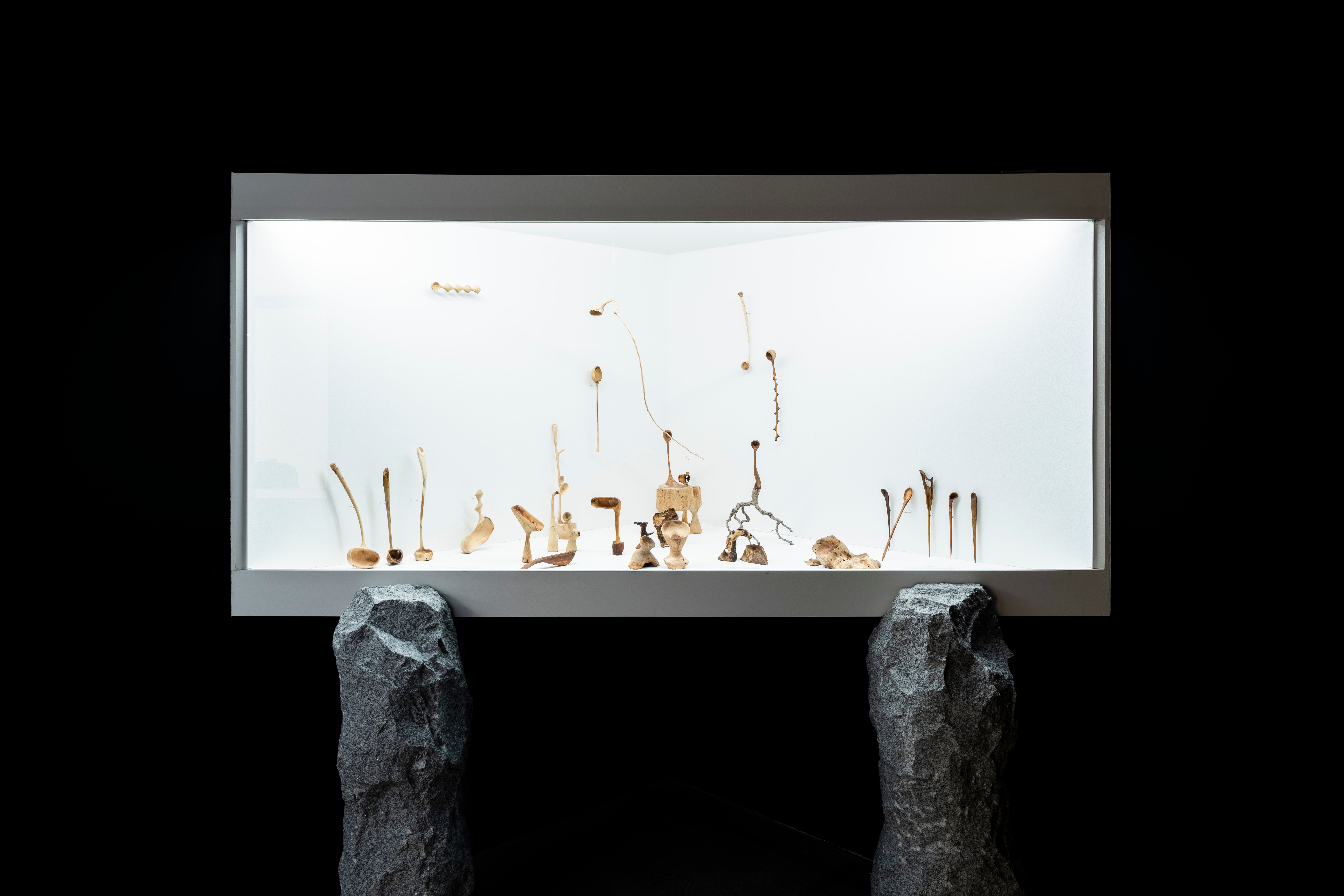An art installation featuring numerous objects displayed on a striking white LED panel raised on stone legs, in the MMCA S...