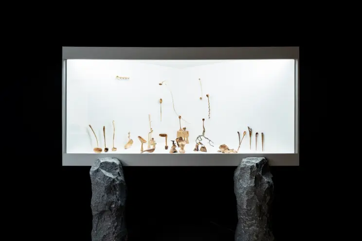 An art installation featuring numerous objects displayed on a striking white LED panel raised on stone legs, in the MMCA S...