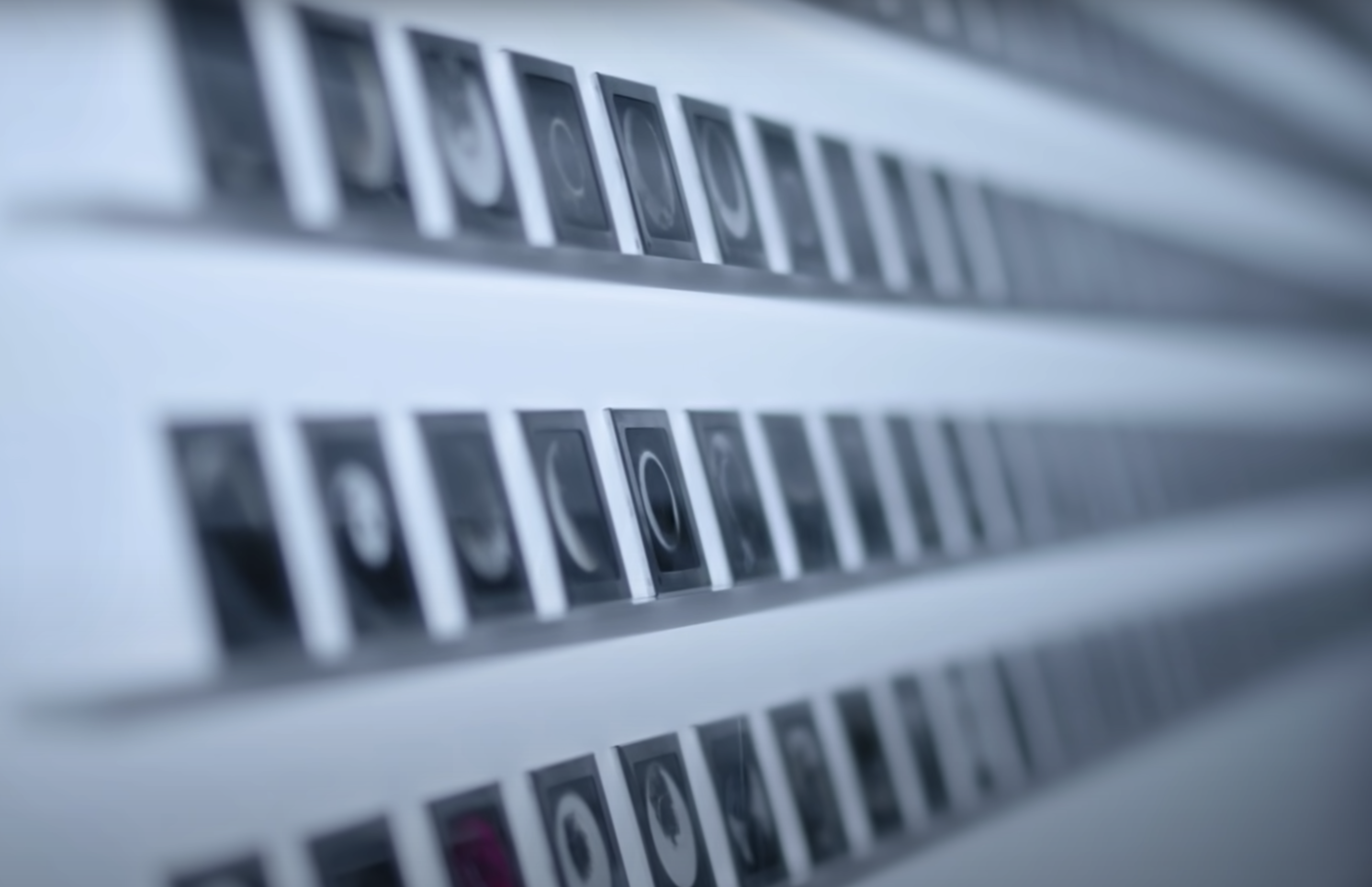 Multiple black and white photographs of the moon displayed on racks against a large, illuminated white panel.