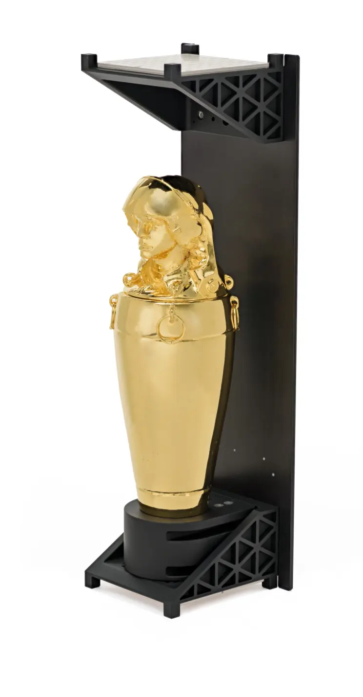 A gold statue is housed within a black display unit. It is in a setting that suggests a professional lab or gallery enviro...
