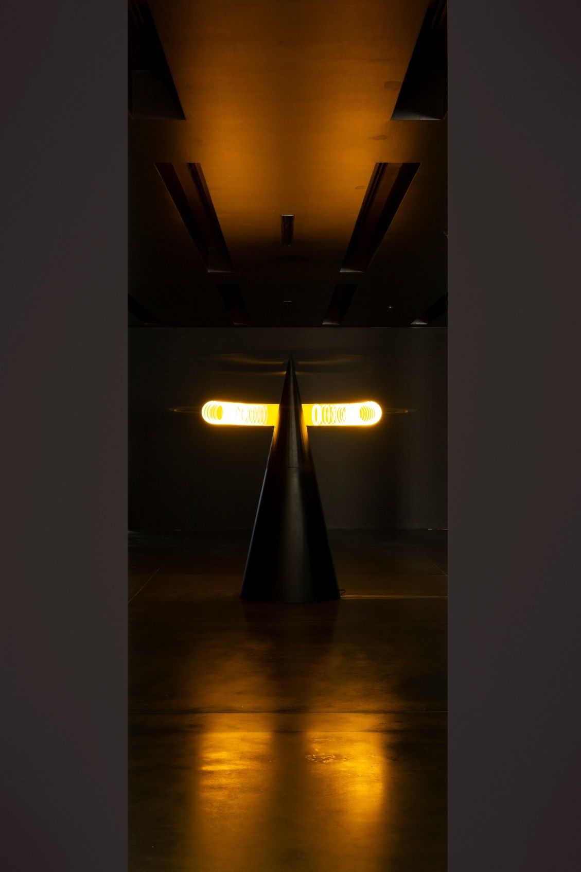 An art piece with a cone and two rings of light on a reflective surface.