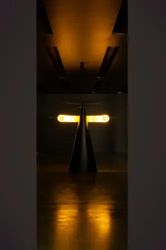 An art piece with a cone and two rings of light on a reflective surface.