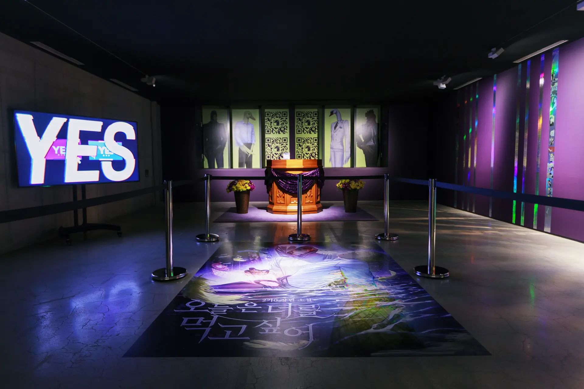 An art gallery with assorted artworks displayed on the walls and floor. A podium and floral arrangement are positioned on ...