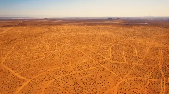 An aerial view of a desert landscape featuring an intricate grid layout of suburban roadlines.