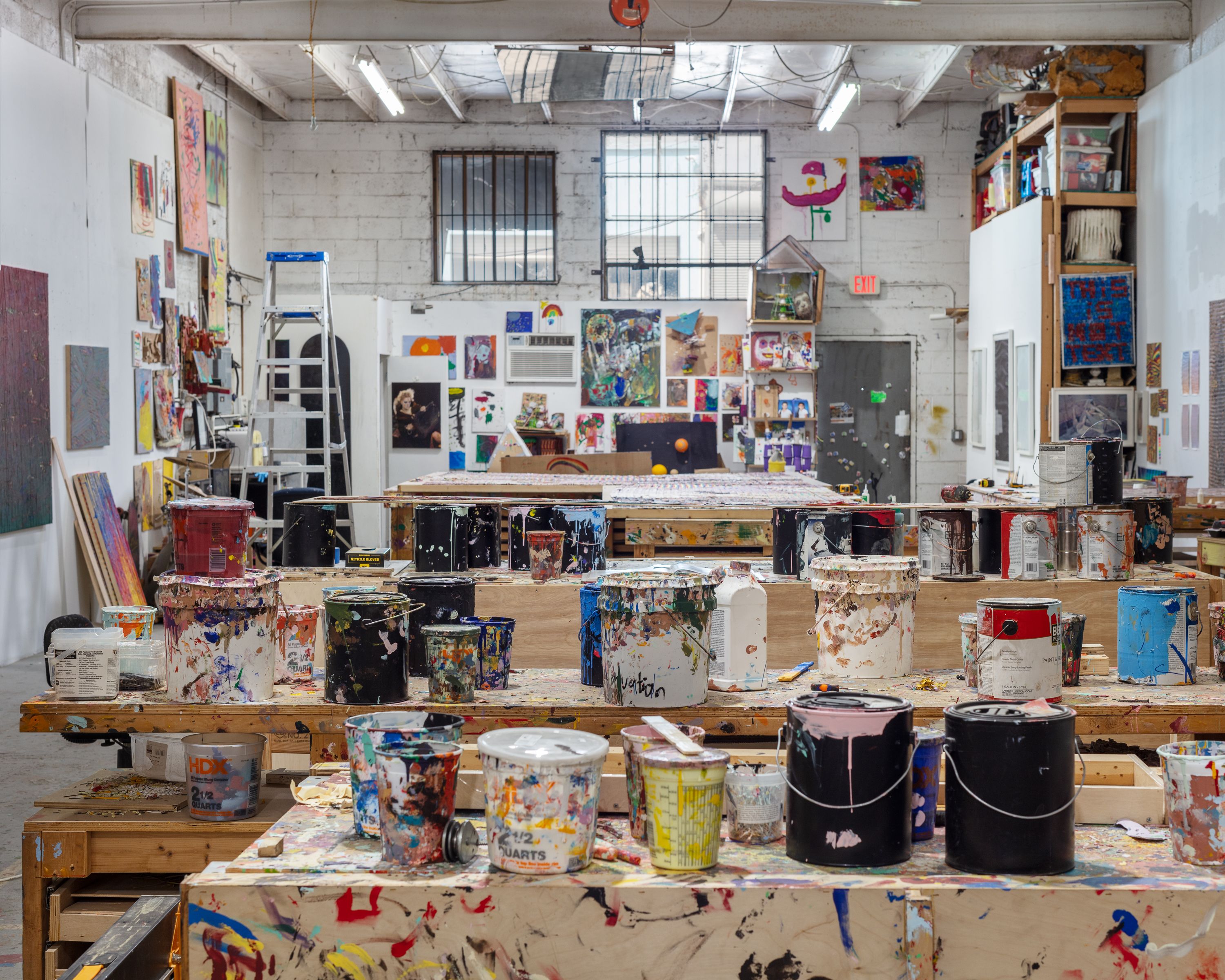 An art studio space containing buckets of paint and work tables.