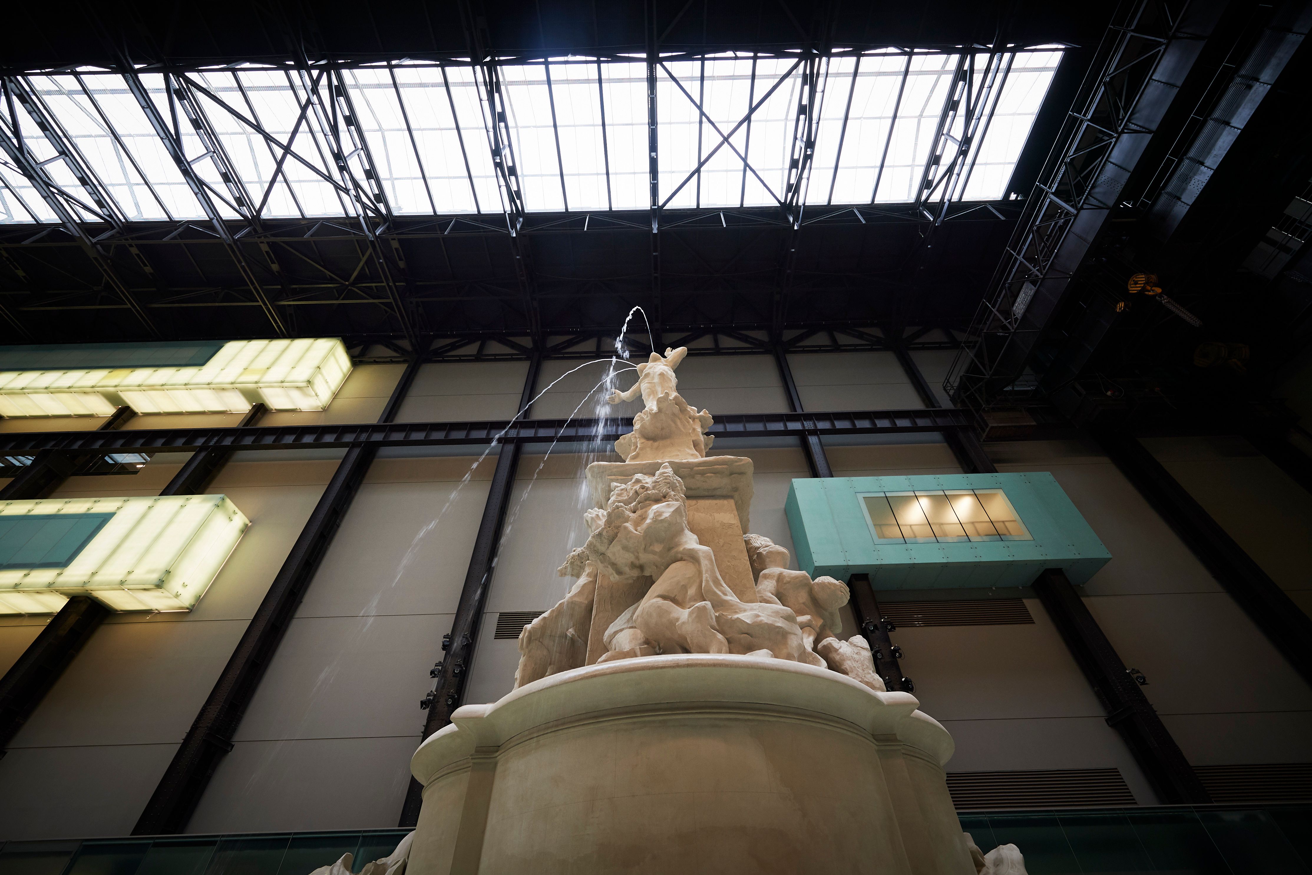 A towering white fountain captured from a frog perspective dominates a spacious gallery hall. The structure is carved intr...