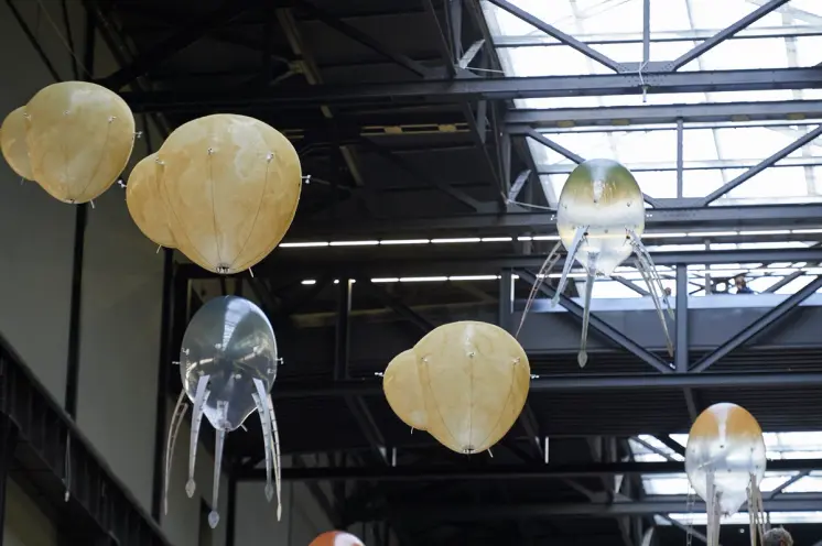 An industrial style installation featuring ceiling lamps shaped like an octopus with snake-headed tentacles. Additional ye...