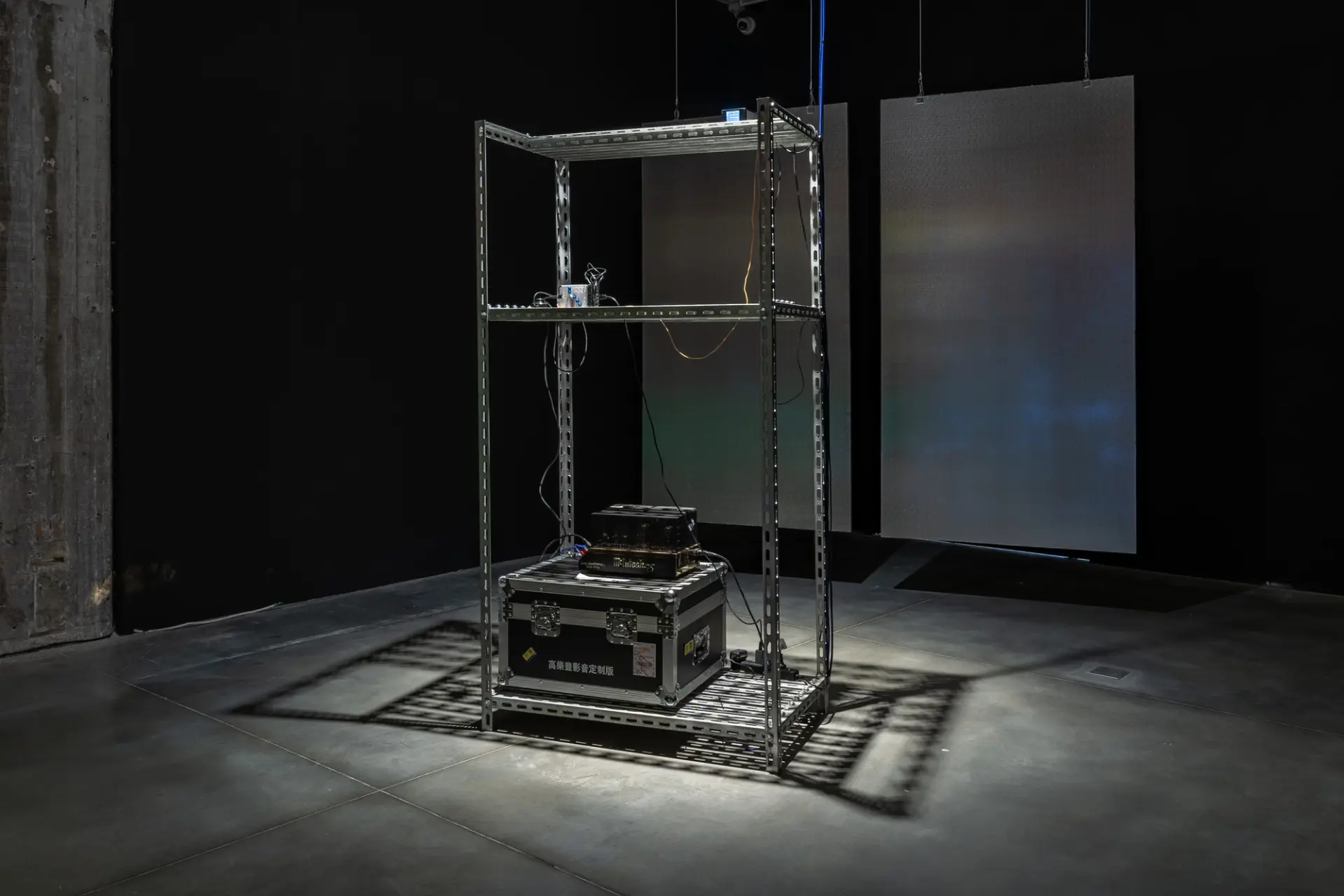 Art installation with metal frame and suspended panels in a dim room.