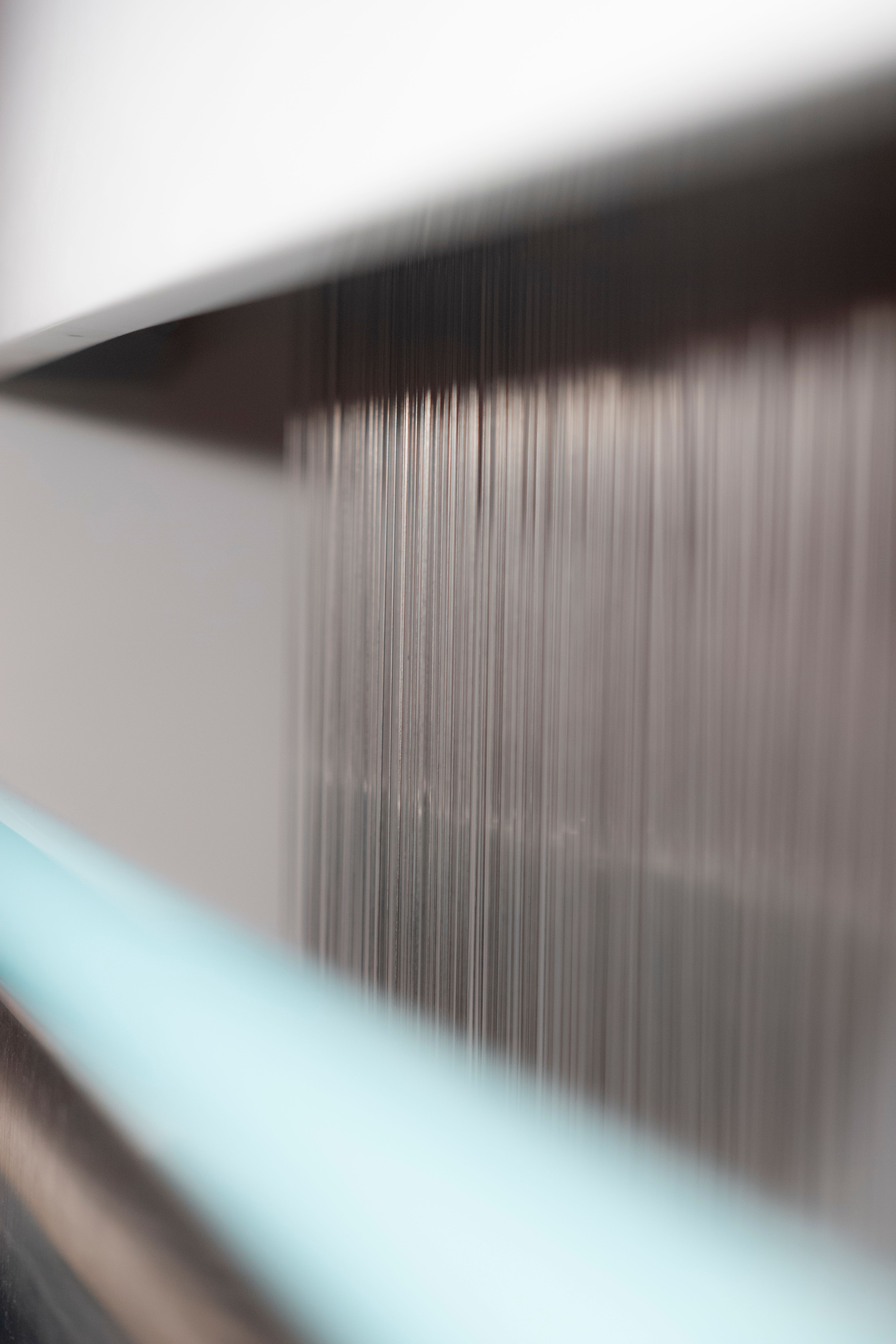 Close-up of a loom's threads in motion, creating a blurred, abstract visual effect.
