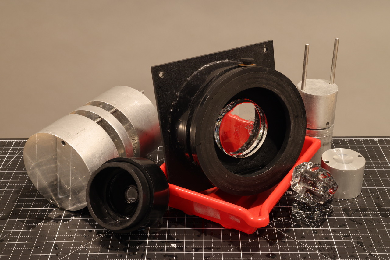 A workshop table covered with various crafting materials including Ice Lenses mounted in fixtures and Ice Lens Molds.