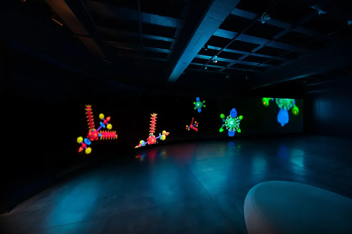 Abstract neon-colored forms resembling chemical elements and satellites displayed in a dimmed room.