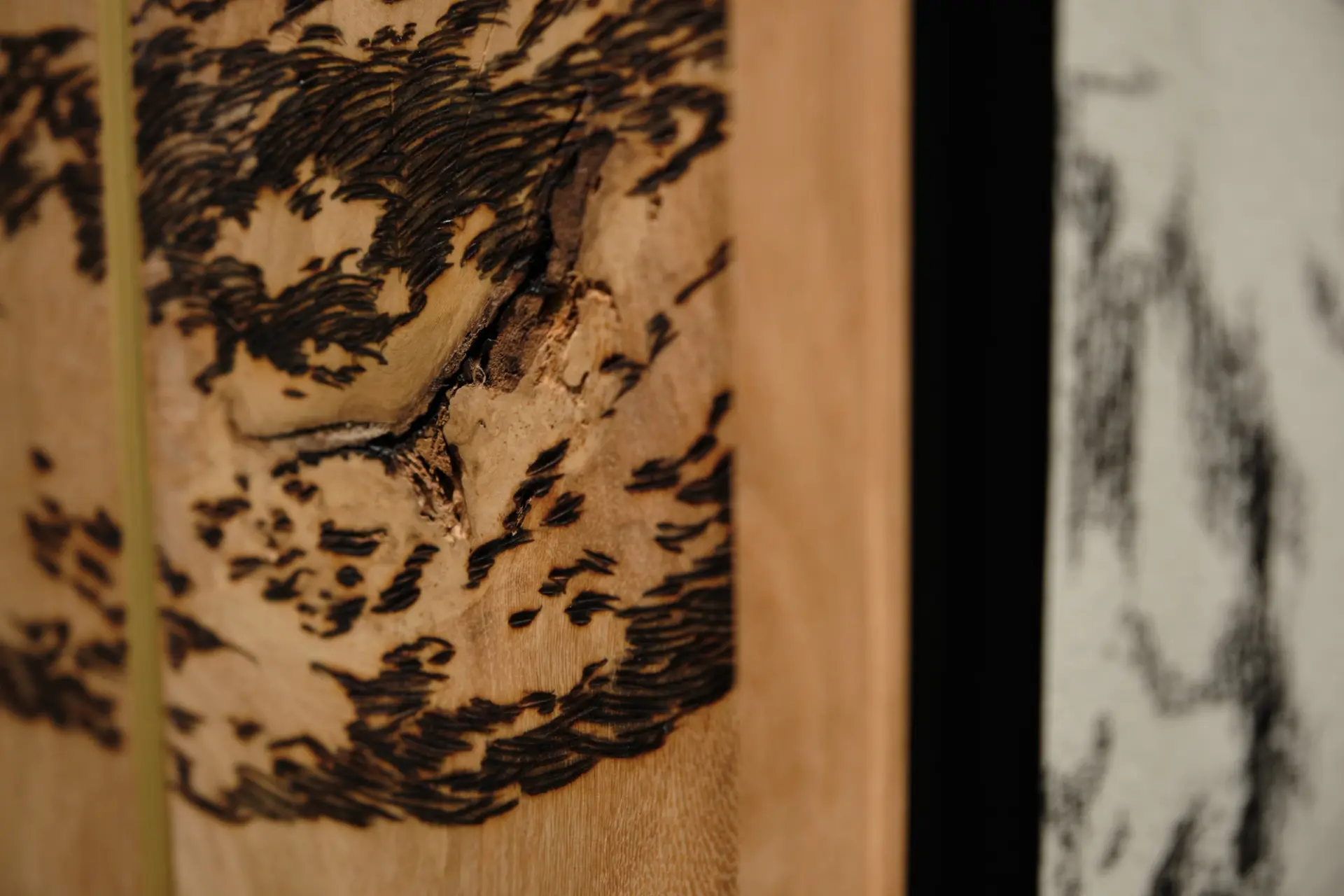 Close-up of a carved and burnt pattern on wood, mimicking tree bark or a branch.