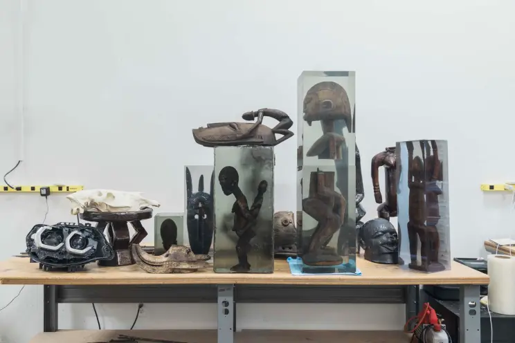 A workshop table populated with a variety of unique sculptures in an array of shapes and materials, set in an artist's stu...