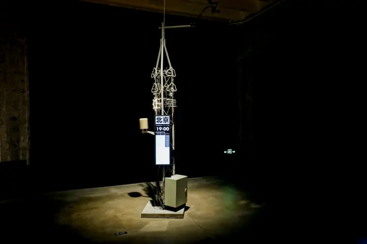 Art installation with hanging skeletal sculptures and digital display.