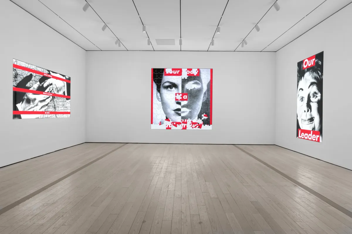 A spacious gallery showcasing black, white, and red photographs featuring human forms and varied texts on the wall.