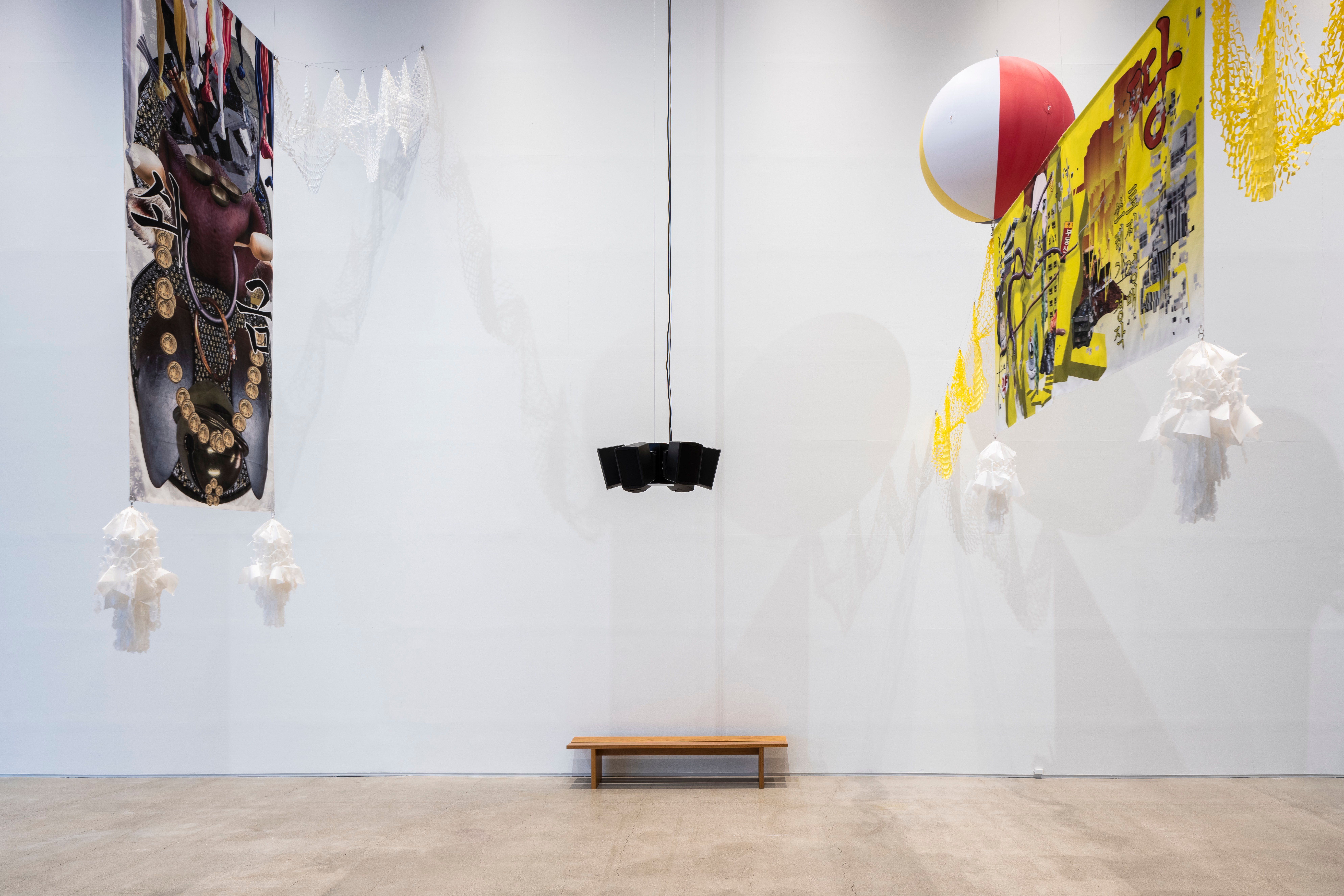 A colorful art installation with patterns suspended from the ceiling amidst two colored balls, white embellishments, and n...