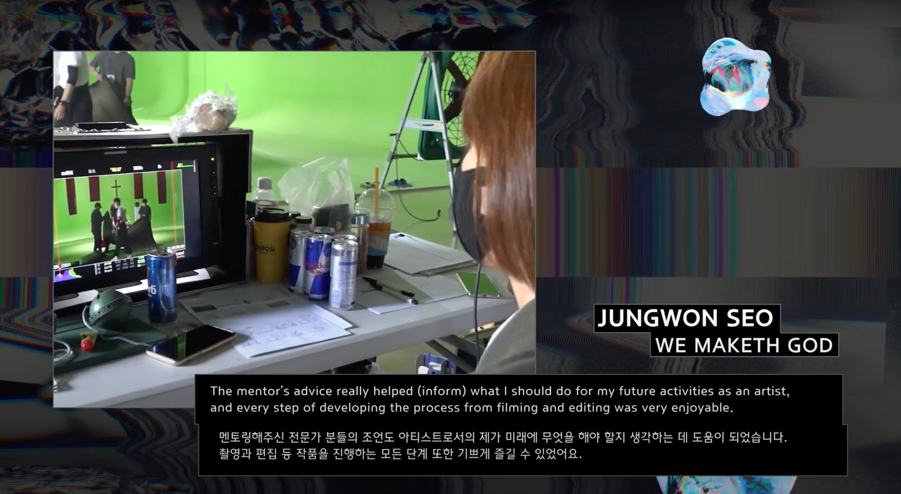 Artist Jungwon Seo sits at a desk in front of a video display, wearing a face mask. The display features a quote from Seo ...