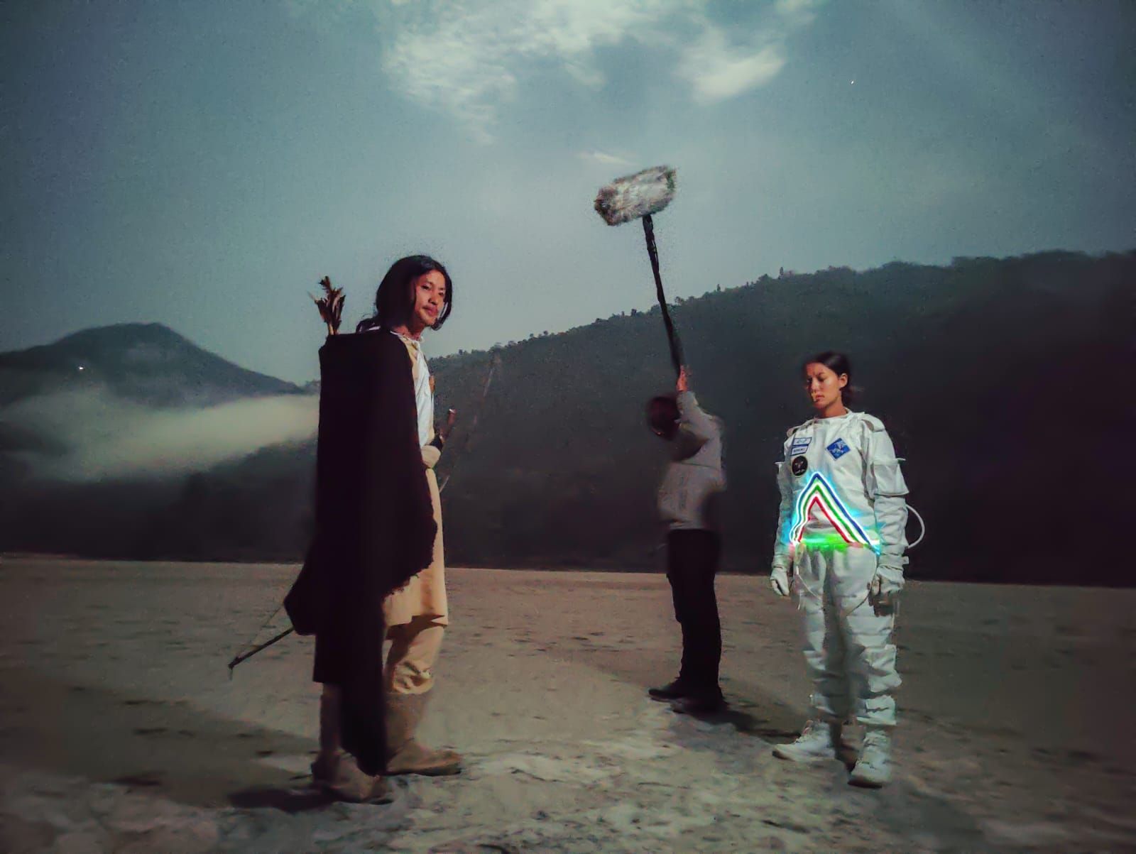 Two individuals performing a scene at dawn, with a third person holding a film recording microphone nearby.