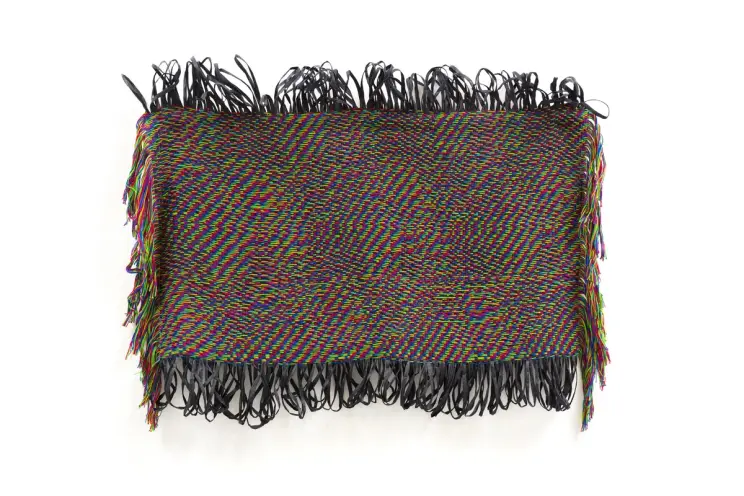 A woven textile artwork with vibrant, glitch-like RGB patterns and black fringe along the edges.