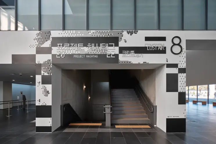 A staircase wall adorned with monochromatic signage showcasing <PROJECT HASHTAG 2022> Gallery Entrance.