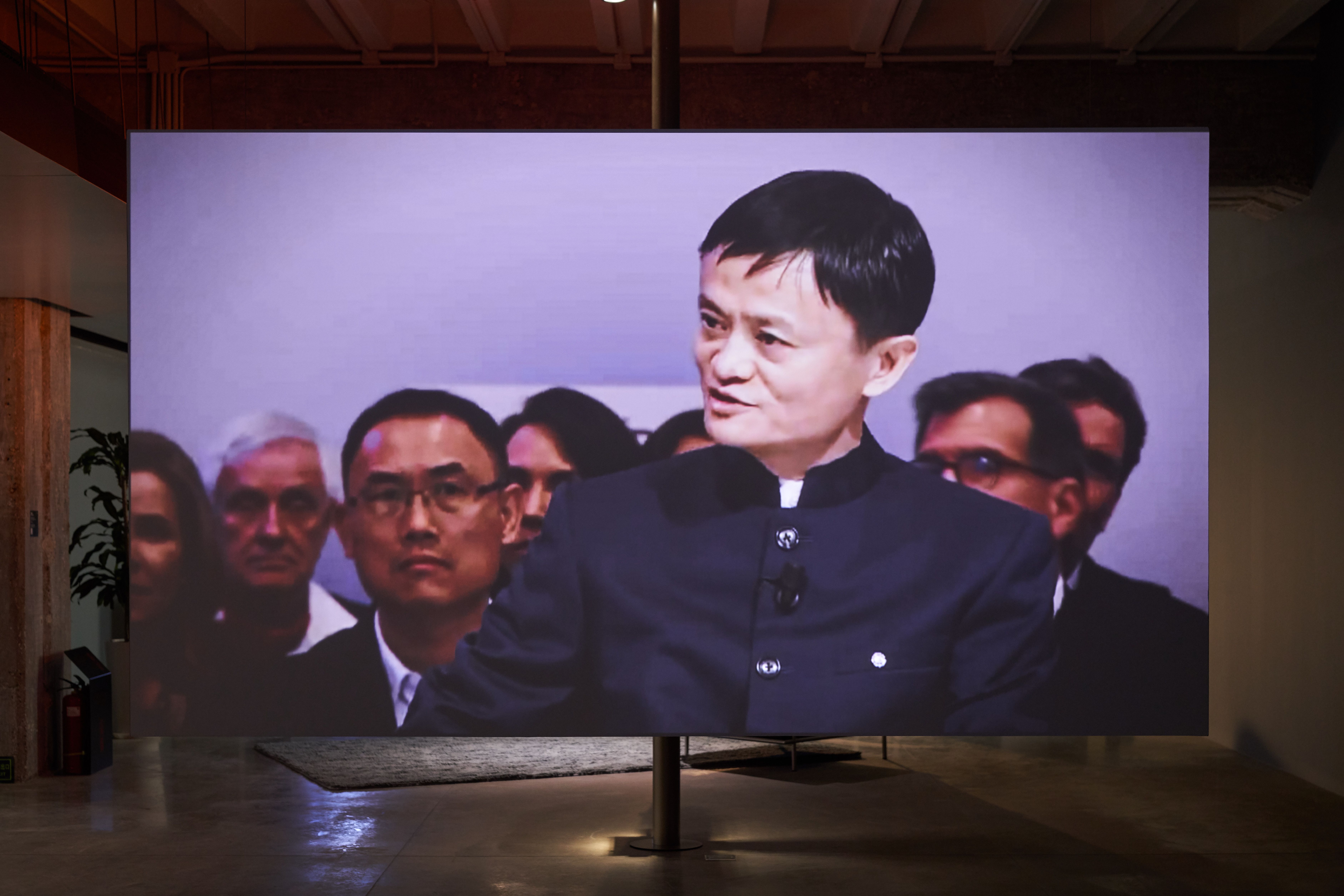 Large screen showing a man in a black outfit in an exhibit.