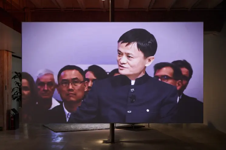 Large screen showing a man in a black outfit in an exhibit.