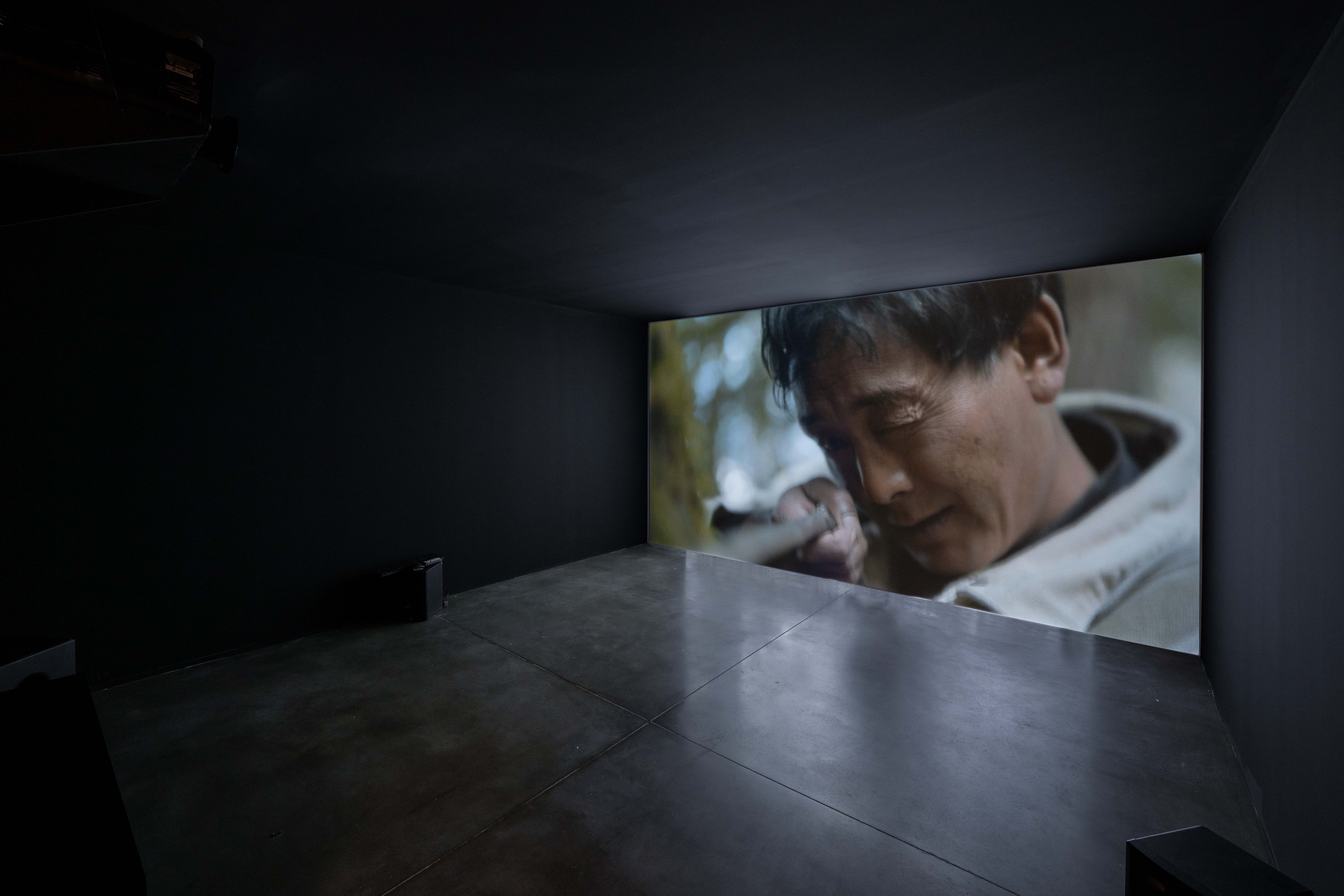 Darkened room with a large screen displaying a close-up of a person's face.