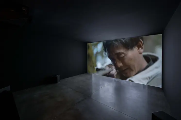 Darkened room with a large screen displaying a close-up of a person's face.