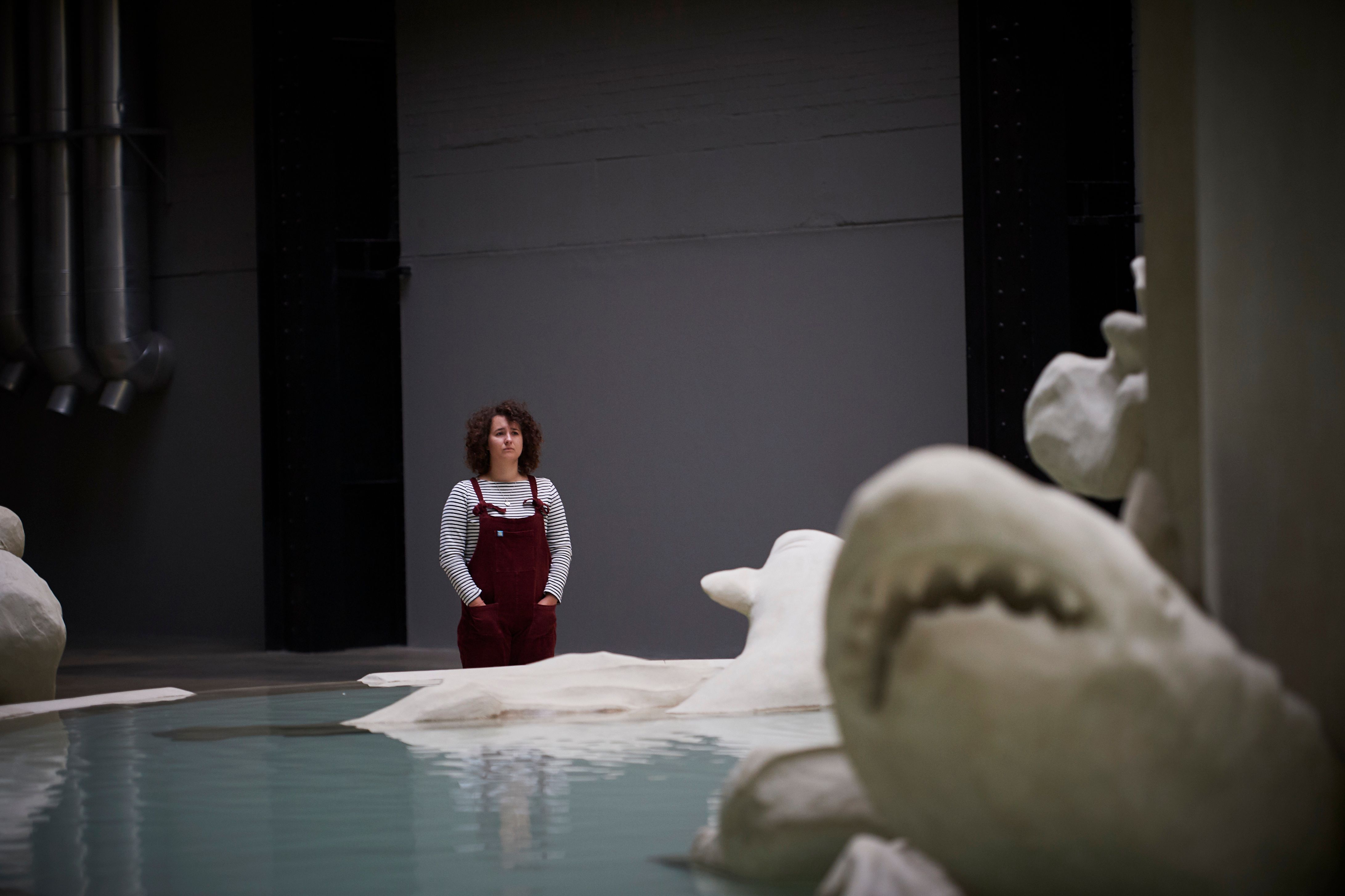 A person stands near the base of a large fountain art installation, observing the details.