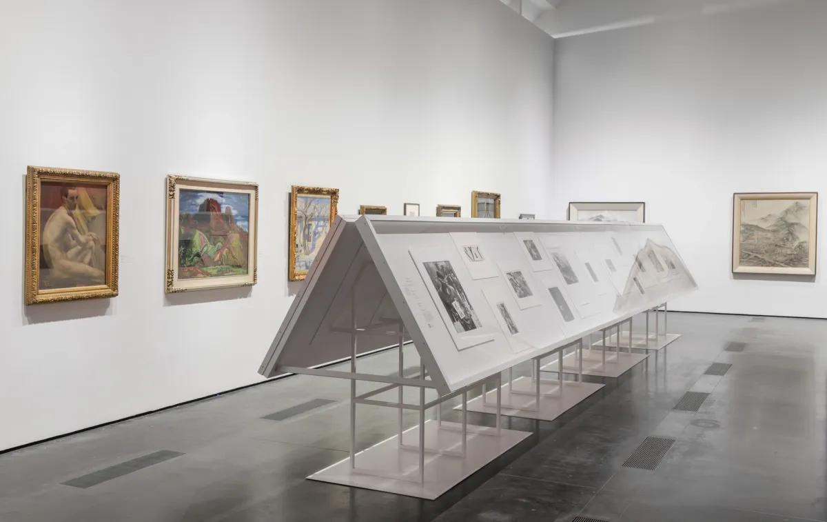 A gallery room displaying art pieces within white frames mounted on metallic stands, a part of the "The Space Between: The Modern in Korean Art" exhibit.