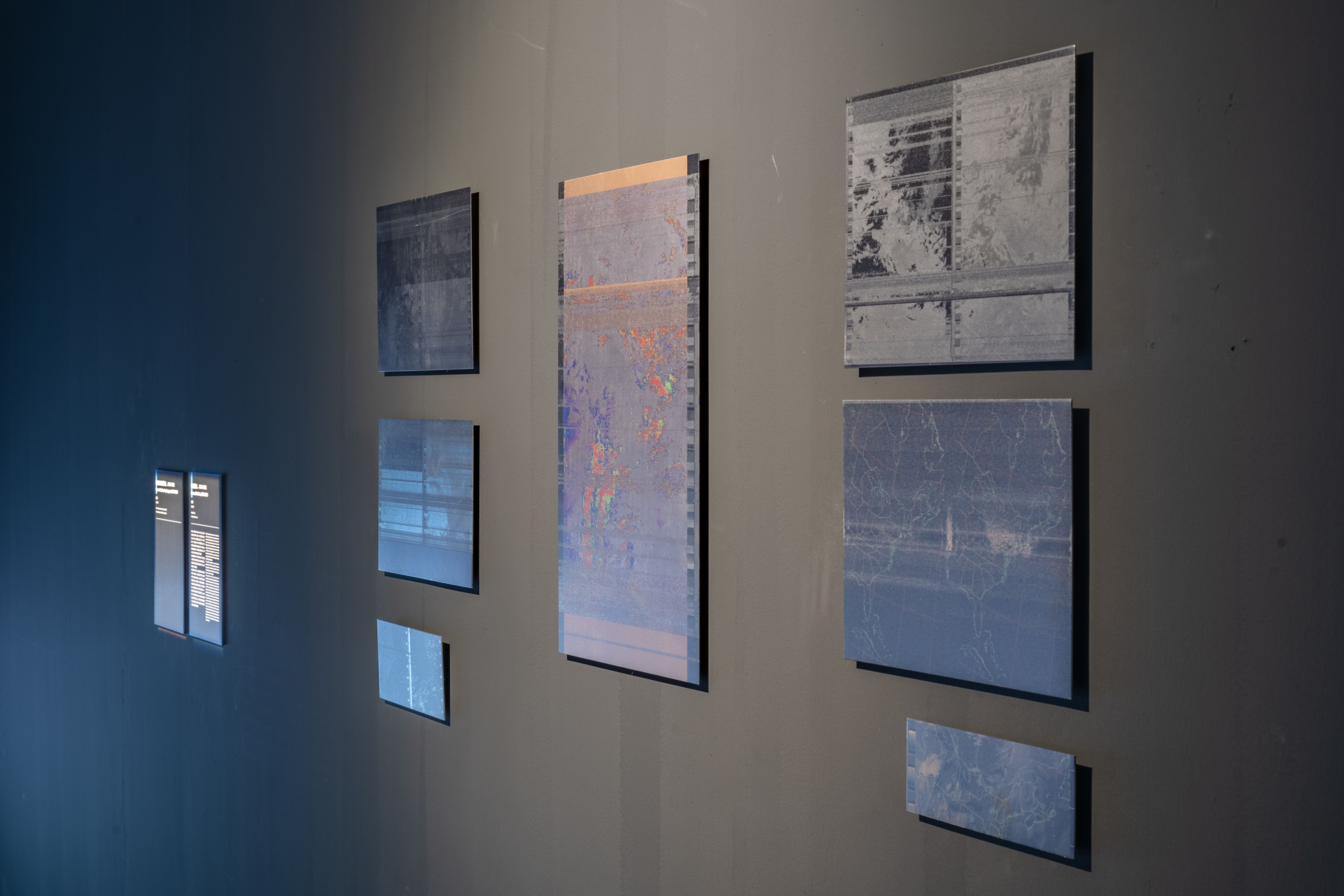 A collection of satellite images displayed on a wall.