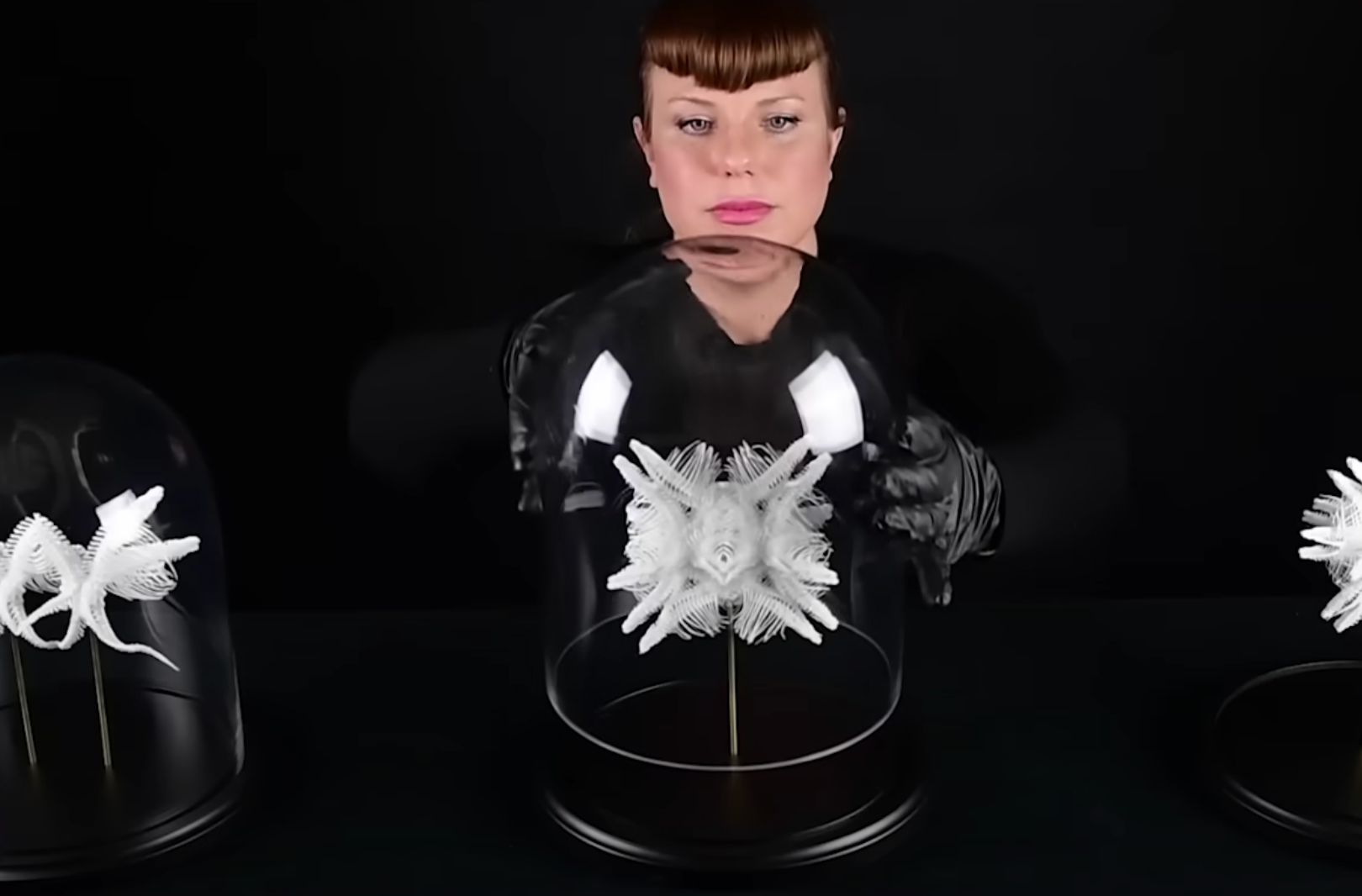 A human figure stands in front of a round glass display dome, which houses a 3D sculpture resembling a snowflake.