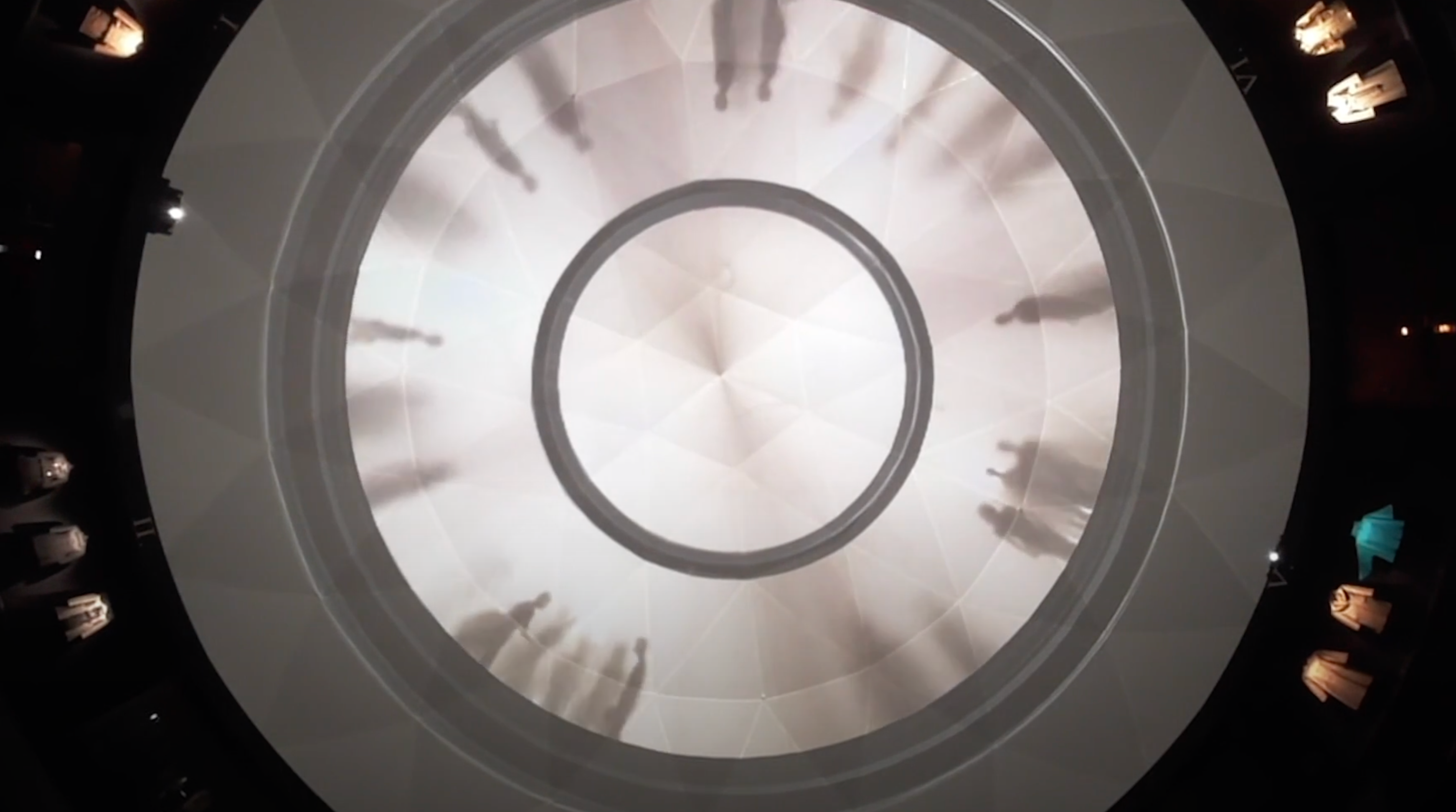 A digital art installation resembling a chandelier, with projections creating a dynamic, kaleidoscopic display.