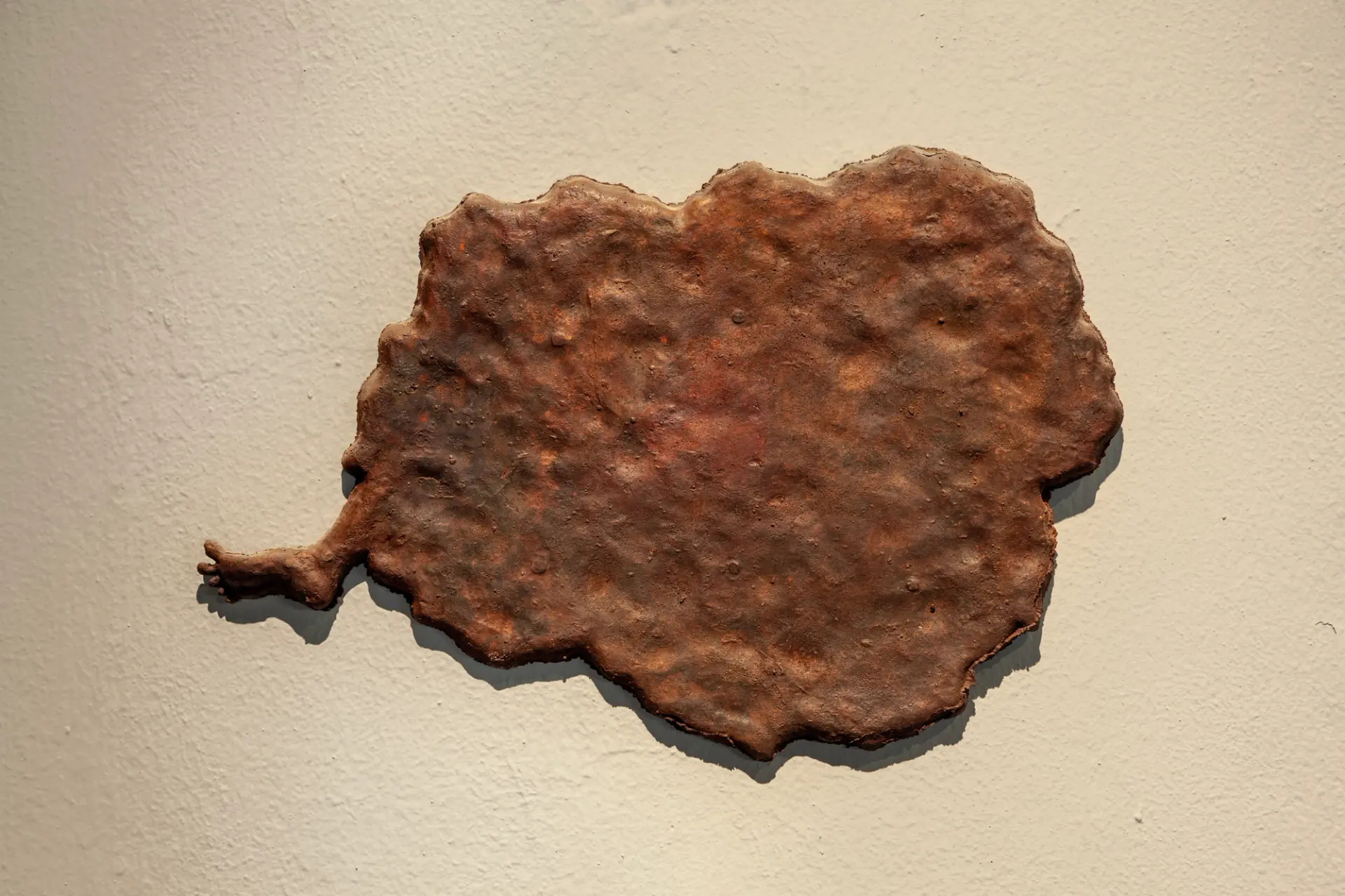A bronze wall hanging with a protruding foot.