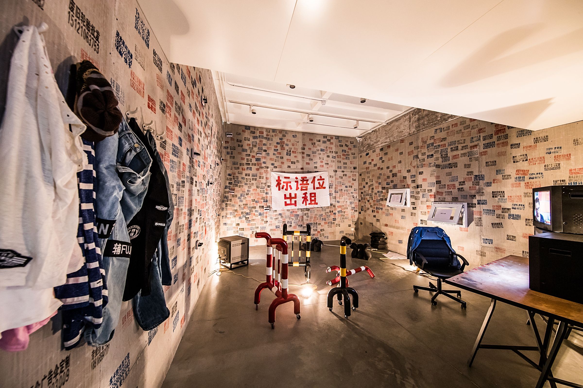 Room with clothes hanging and papers on walls.