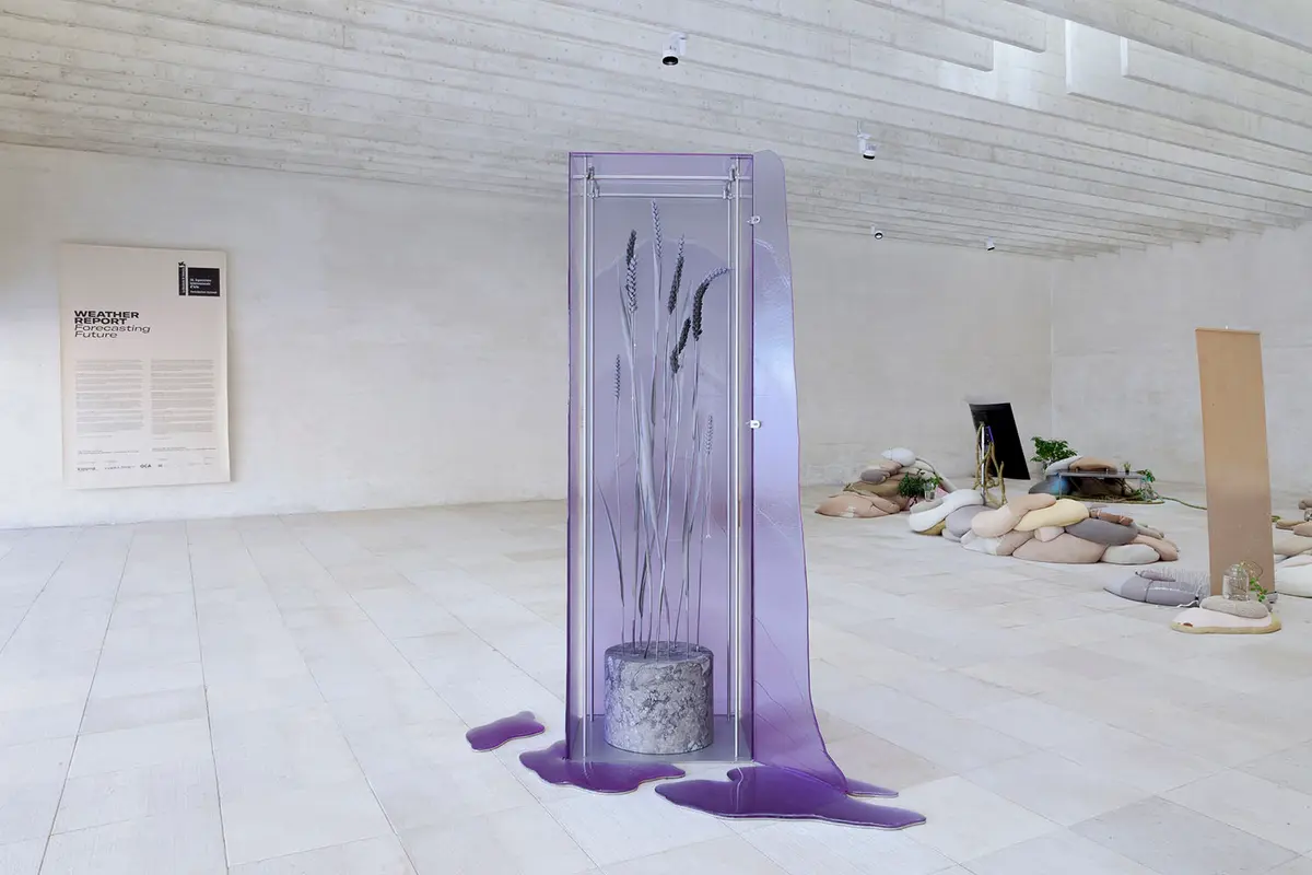 An art installation of lavender structure encased in transparent purple glass, situated in a bright white gallery.