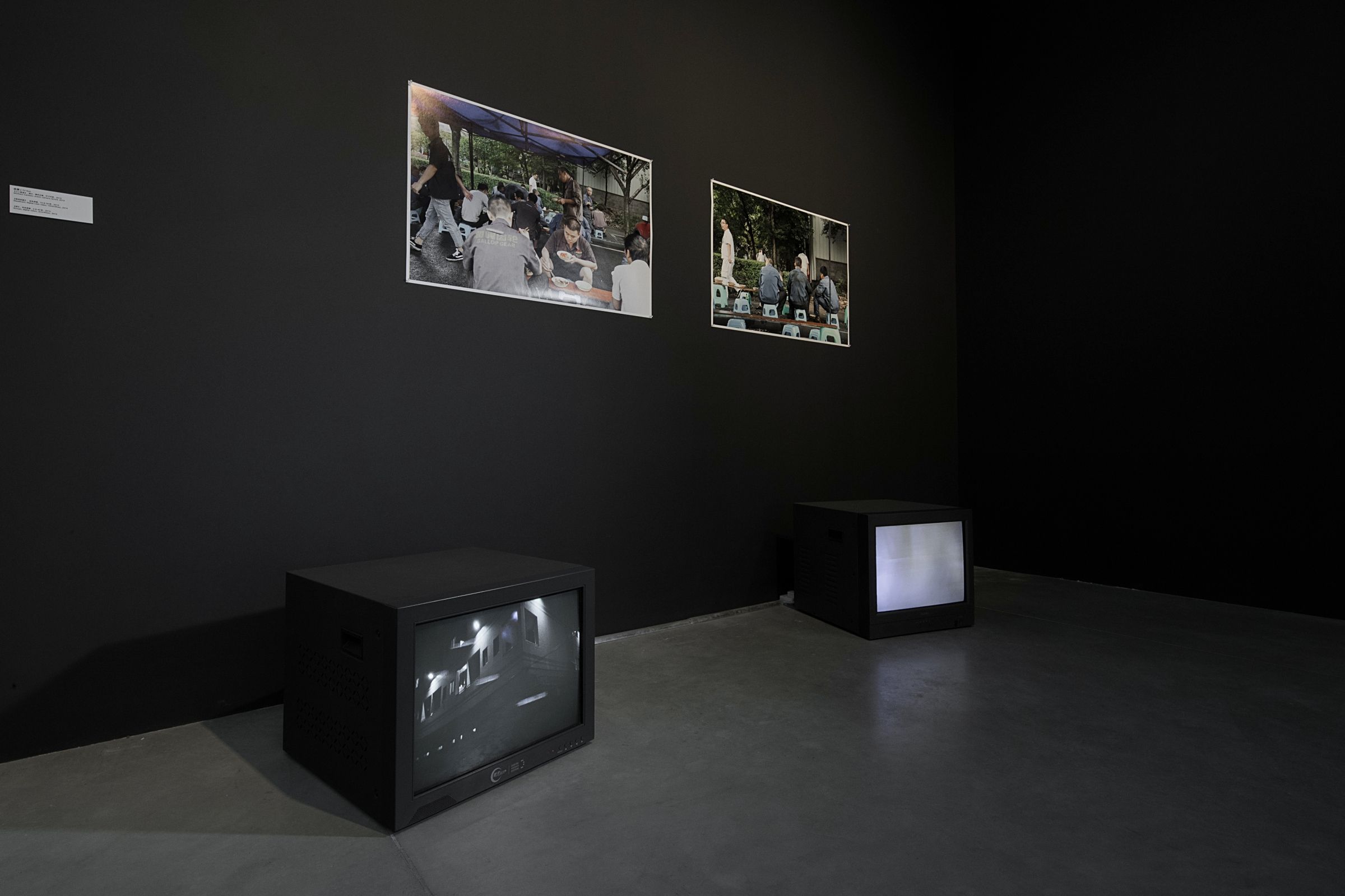 Dark room with photos on wall and TVs on floor.