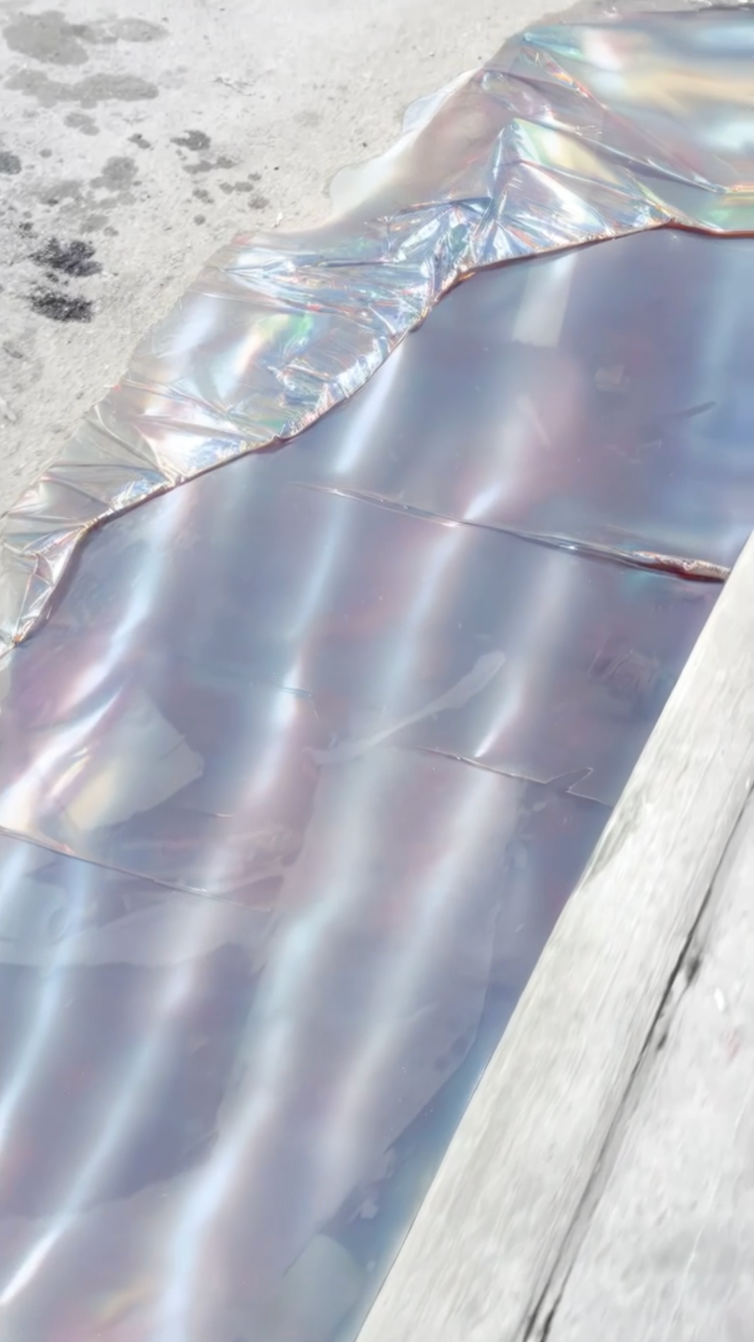 Close-up of a digital, liquid reflective surface on asphalt.