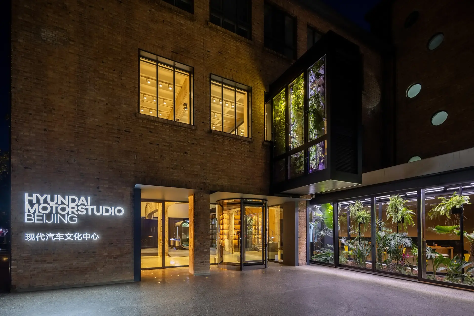 Nighttime view of the entrance to Hyundai Motorstudio Beijing, a modern cultural space housed in a brick building. Illumin...