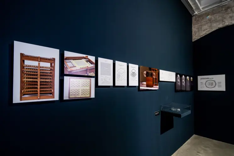 Gallery wall with framed drawings and diagrams next to a display case.