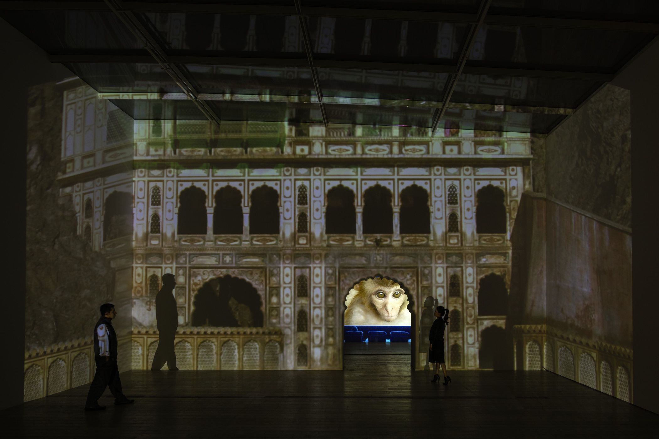 A projection on the wall displaying an image of an old architectural structure alongside a screen that shows a monkey.