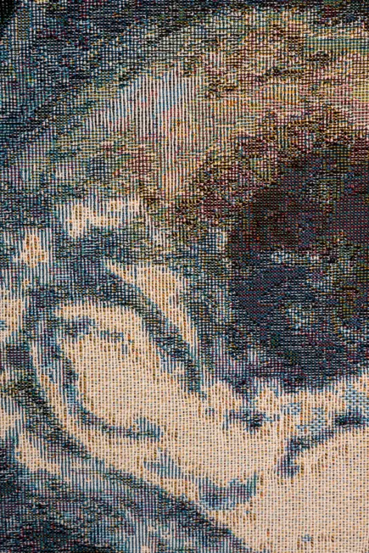 A close-up of a detailed, textured woven artwork with a colorful pattern resembling abstract landscapes.