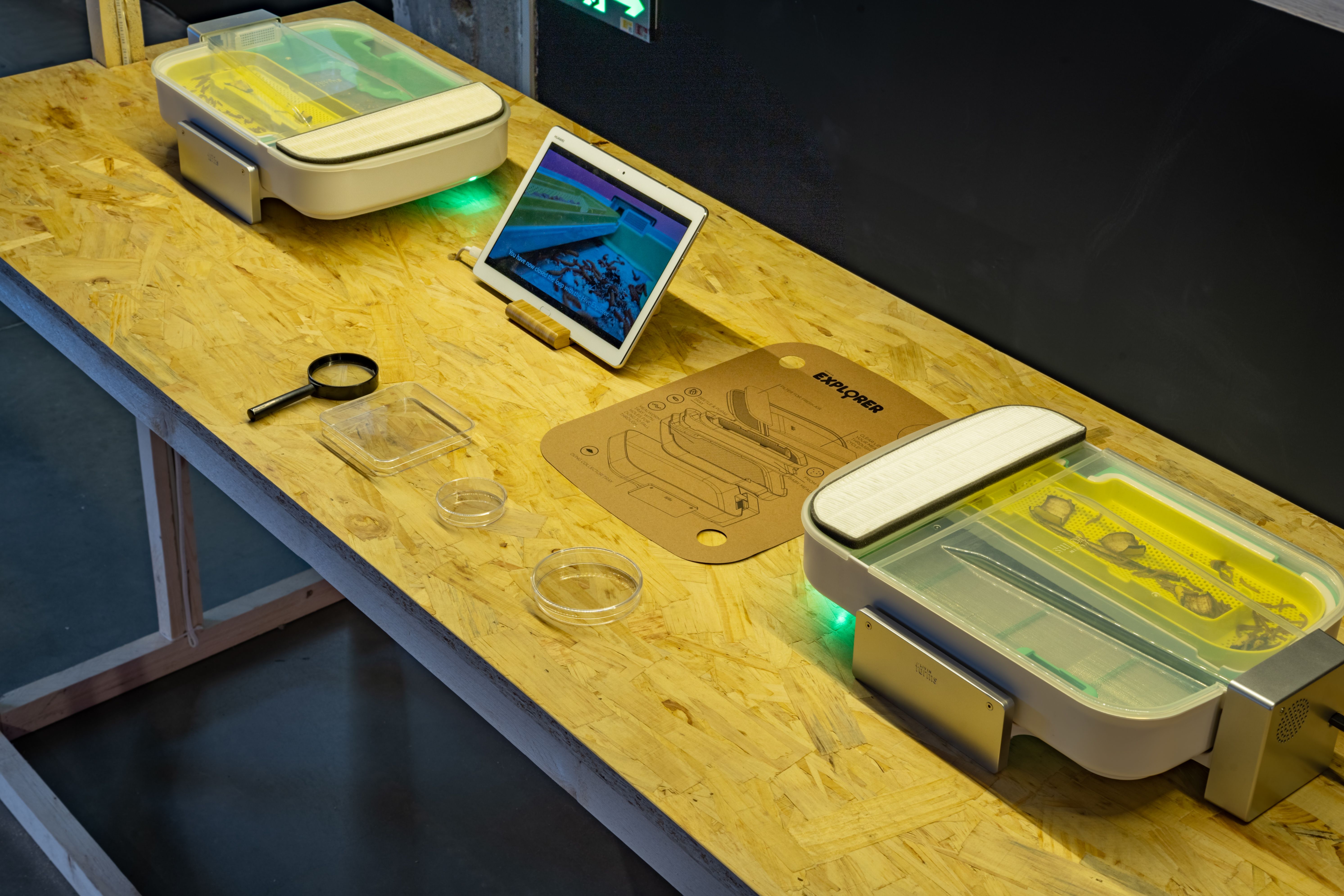 Close-up of a lab setup with magnifying glass, tablet, and experiment kit.