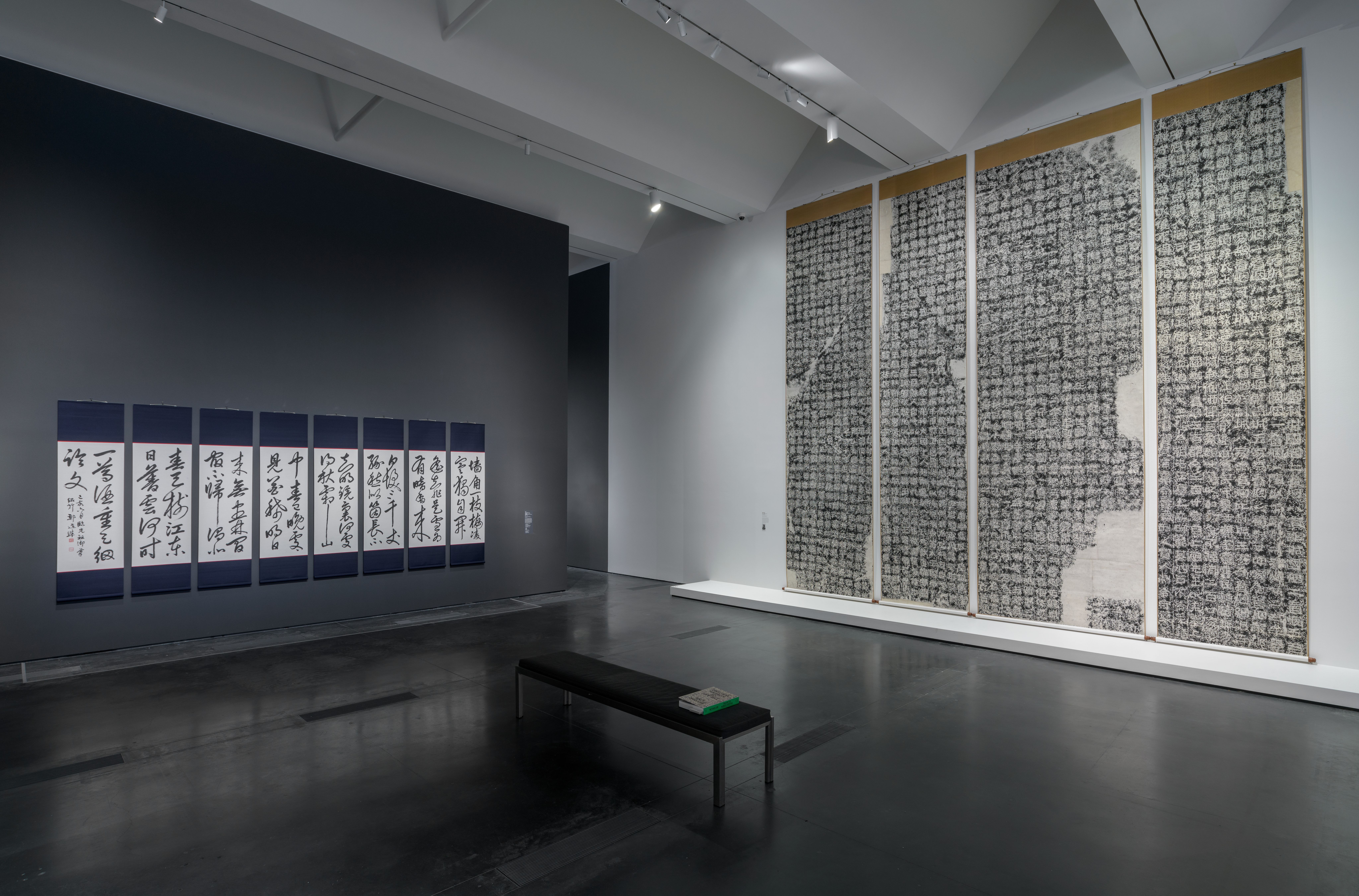 Exhibition gallery at Los Angeles County Museum of Art, featuring art pieces hung on walls, a dark flooring, and a central...