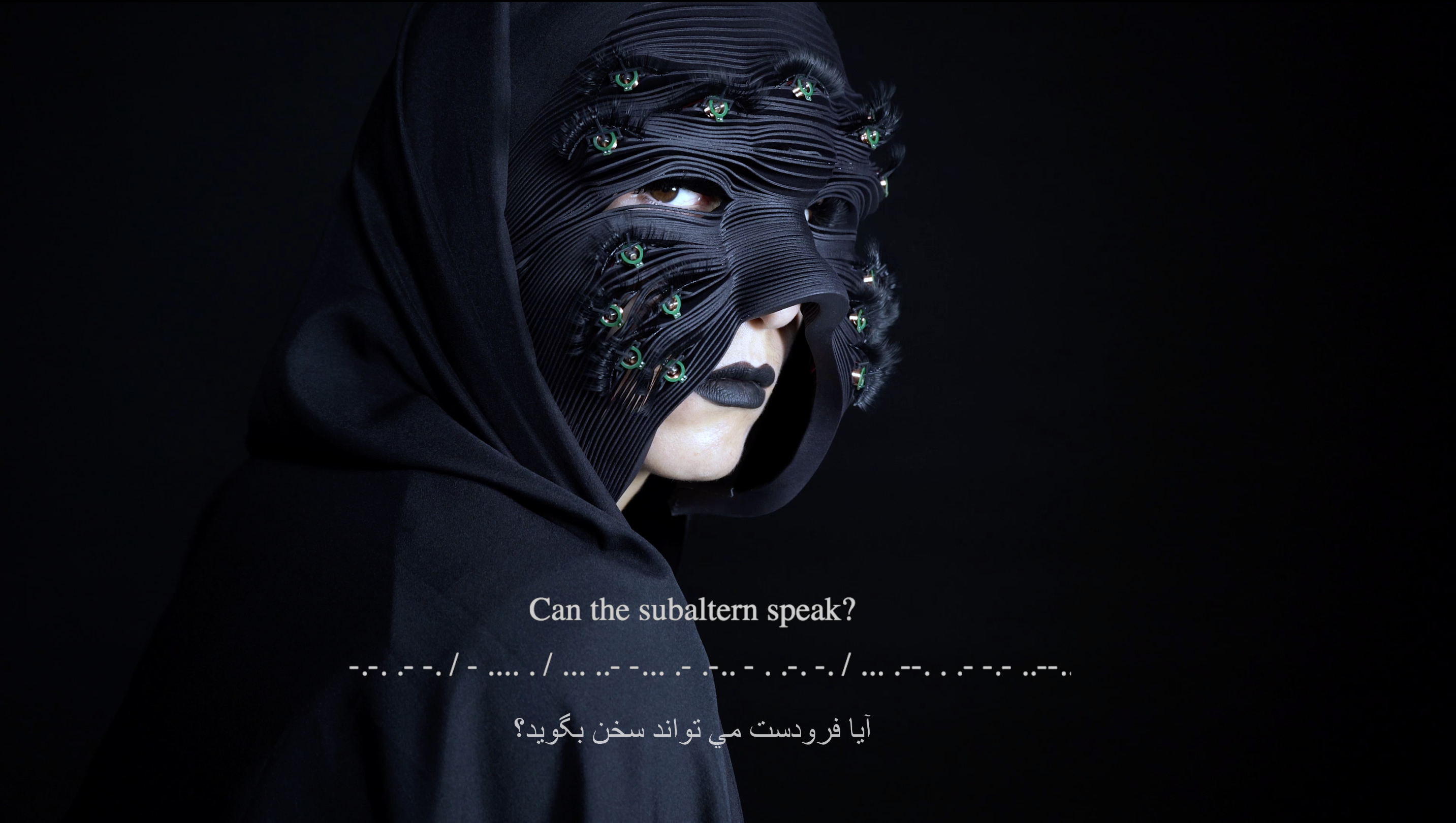 A person wearing a black mask with electronic elements and green lights, posing against a dark background with the question "Can the subaltern speak?" in English and Arabic.