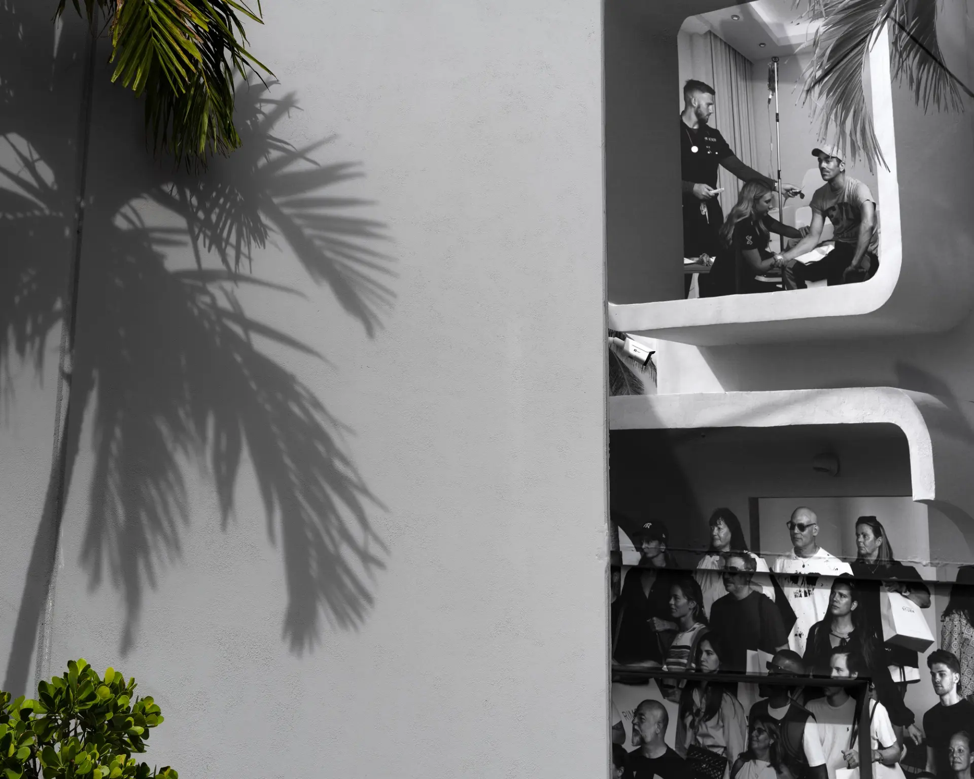Black and white photo of people in modern building balconies, sunny day.